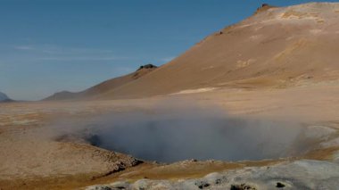 İzlanda 'daki Myvatn Gölü yakınlarındaki Hver' deki diğer dünyaların jeotermal özelliklerini araştırın. Mavi gökyüzünün altında dumanı tüten fümeroller ve canlı mineral birikintileri..