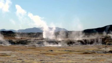 Hver İzlanda 'da nefes kesici bir jeotermal alan yerden yükselen dalgalı buhar bulutlarını ortaya çıkarıyor, engebeli dağlarla çevrili..