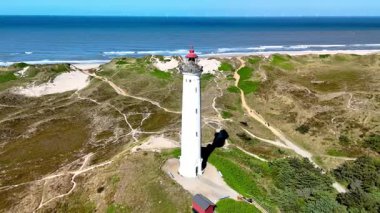 Danimarka 'nın Jutland kentindeki Lyngvig Deniz Feneri Hvide Sande' nin altın kum ve gök mavisi sularıyla nefes kesici manzarasını keşfedin. Yüksek bir beyaz deniz feneri gururla durur kıyı manzarasına karşı