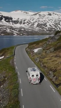 Bir karavan, görkemli dağlar ve dingin göllerle çevrili dolambaçlı bir yolda giderken Norveç 'in huzurlu manzarasını keşfedin. Norveç Sahne Yolu Geiranger-Trollstigen 