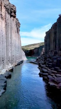 İzlanda 'daki Studlagil Kanyonu' nun kristal berrak suları dramatik bazalt sütunları arasında sakin bir kaçış yaratır..
