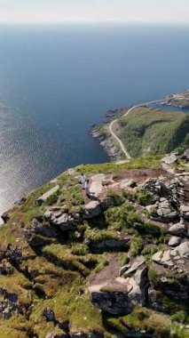Reinebringen Lofoten Norveç 'teki engebeli bir uçurumun tepesinde durarak engin okyanusa ve uzak kıyılara hayret ediyorum. Güneş, suyun üzerine güzel bir parıltı saçar ve dingin bir atmosfer yaratır..