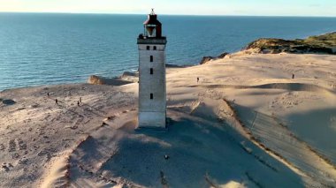Rubjerg Knude Fyr Deniz fenerinin büyüleyici manzaralarını keşfedin, altın kumların denizle buluştuğu Jutland Danimarka 'daki ikonik deniz fenerini vurguluyor.