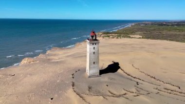 Danimarka, Jutland 'daki Rubjerg Knude Fyr Deniz Feneri' nin çarpıcı kıyı manzarası. Altın kumlar, dalgalar ve Danimarka 'daki tarihi deniz feneri.