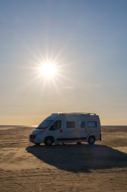 Lakolk Strand, Romo, 11 Mayıs 2025, Danimarka, plaja park etmiş bir karavan, akşam güneşinin sıcacık parıltısıyla yıkanmış.. 