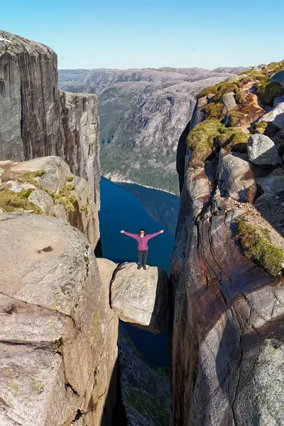 Kayalık bir çıkıntının üzerinde duran bir maceraperest Norveç 'in büyüleyici fiyortlarını gözden kaçırır. Kjeragbolten Lysefjord, Norveç