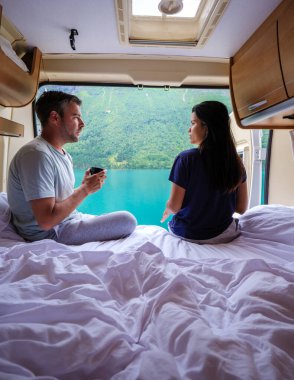 Bir çift, karavanda rahat rahat oturup dışarıdaki fiyort manzarasına bakarken sıcak bir içkinin tadını çıkarıyor. Lovatnet Norveç 'te karavanda kalan bir çift erkek.