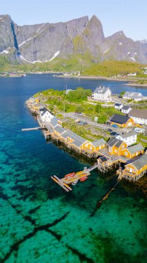 Fiyortlarda yuva yapmış, Lofoten Norveç 'te Reine kristal berrak suların üzerinde renkli ahşap evler sergiliyor..