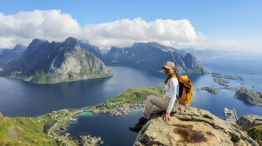 Bu nefes kesici manzara kayalık bir çıkıntıya tünemiş bir gezgini yakalar. Görkemli dağlara ve Norveç Lofoten Adaları 'nın sakin sularına bakar..