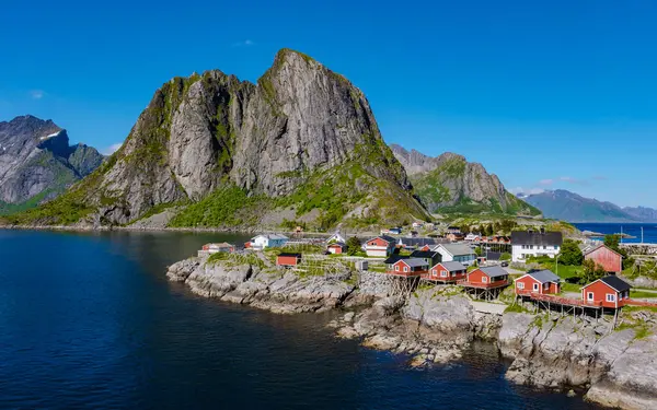 Norveç 'in dingin, kırmızı balıkçı kulübelerinin yükselen dağlara dayandığı kıyı şeridini keşfedin. Hamnoy, Lofoten, Norveç 'teki balıkçı köyü