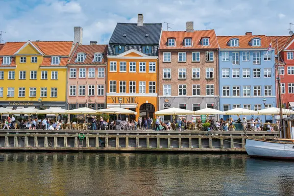 Nyhavn, Kopenhag, Danimarka, 12 Temmuz 204: Canlı binalar büyüleyici bir kasabanın rıhtımında, açık hava yemeklerini ve boş boş gezintileri seven insanlarla dolanıyor..