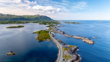 Norveç 'te, berrak mavi suların engebeli adalarla buluştuğu nefes kesici bir kıyı manzarası keşfedin. Manzarası kıyı şeridi boyunca sükuneti yakalıyor. Parlak bir gökyüzü altında, Atlantik Okyanusu Yolu, Norveç