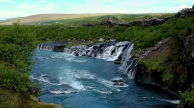 Barnafoss ve Hraunfossar 'ın İzlanda' daki lav oluşumlarına zarifçe akışına tanık olun. Bu doğal mucize canlı renkler ve çarpıcı manzara görüntülerini sergiliyor..