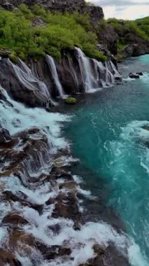 Sersemletici Barnafoss ve Hraunfossar şelalelerini keşfedin. Turkuaz suları, İzlanda 'nın sakin topraklarındaki yemyeşil yemyeşil sularla çevrili lav oluşumlarının üzerine dökülür..