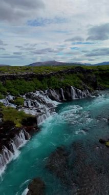 İzlanda 'nın doğal güzelliğini, berrak suların Barnafoss ve Hraunfossar' daki eşsiz kaya oluşumları üzerinde dalgalanırken tecrübe edin. Bu çarpıcı şelaleler yemyeşil ortamda büyüleyici manzaralar yaratır..