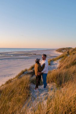 Bir çift uzun otlarla çevrili kumlu bir kumulda birbirine yakın duruyor. Blokhus Strand Sahili Danimarka