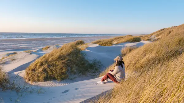 Blokhus Strand, Danimarka 'da sakin bir plajda altın kum tepeleri ve yumuşak okyanus dalgaları bulunur. Bir insan, altın saat boyunca doğanın güzelliği içinde huzurlu bir atmosferin tadını çıkarır..
