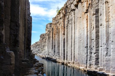 Ziyaretçiler İzlanda 'daki Studlagil Kanyonu' nun nefes kesici bazalt kolonları ve sakin sularına hayret ediyorlar. Dramatik manzara doğa severler ve fotoğrafçılar için nefes kesici bir macera sunuyor..