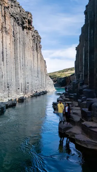 Ziyaretçiler, bazalt sütun duvarları ve kristal berrak sularla çevrili Studlagil Kanyonu 'nun çarpıcı jeolojik oluşumlarını keşfediyorlar..