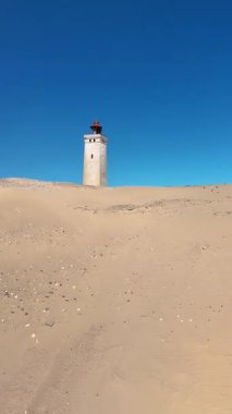 Rubjerg Knude Fyr Deniz Feneri 'ne sonsuz sayıda altın kum ziyaretçisi geliyor. Tarihi bir deniz feneri gururla duruyor Danimarka 'da canlı bir mavi gökyüzüne karşı