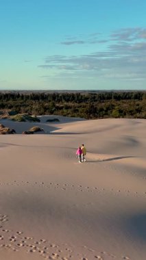 Çiftler Danimarka 'nın Jutland kentindeki çarpıcı Rabjerg Mile kum tepelerinde dolaşıyorlar. Hafif bir esinti ve canlı bir manzara şehir hayatından barışçıl bir kaçış yaratır.