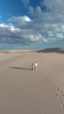 Rabjerg Mile Jutland, Danimarka 'nın engin kumullarında birlikte yürüyen bir çift geride ayak izleri bırakıyor. Gökyüzü dramatik bulutlarla dolu.