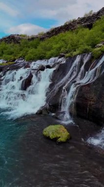 Barnafoss ve Hraunfossar şelalelerinin büyüleyici akışını keşfedin, İzlanda 'nın yemyeşil yeşillikleriyle çevrili karanlık volkanik kayaların üzerinde çağlayarak, doğa severler için mükemmel.