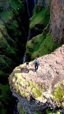 İki maceracı İzlanda 'da nefes kesen bir uçurumun kenarında, dramatik bir kanyona bakan. İzlanda 'daki Glymur şelalesi kanyonu