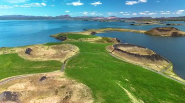 İzlanda 'daki Myvatn Gölü' nün eşsiz manzarasını deneyin. Parlak bir gökyüzü altında yemyeşil lav tarlaları ve durgun mavi sular..
