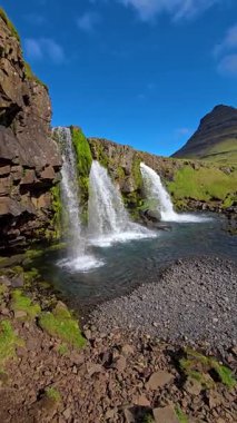İki görkemli şelale zarif bir şekilde yemyeşil ve engebeli dağlarla çevrili sakin bir nehre akıyor. İzlanda 'nın doğal güzelliğinin mükemmel bir örneği, Kirkjufell İzlanda