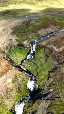 İzlanda 'daki Selvallafoss şelalesini keşfedin. Suyun zarif bir şekilde kayalıklardan yuvarlandığı, yemyeşil tepelerle çevrili..