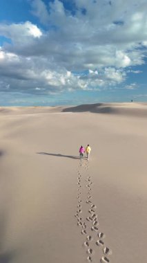 İki kişi, Danimarka 'nın Rabjerg Mile Jutland kentindeki geniş kum tepelerinde birlikte yürür..