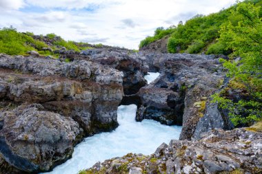 Bereketli yeşilliklerle çevrili Barnafoss ve Hraunfossar 'daki kayalık oluşumlarda sersemletici şelaleler çağlıyor. Nehir güçlü bir şekilde akar ve İzlanda 'nın doğasında büyüleyici bir manzara yaratır.