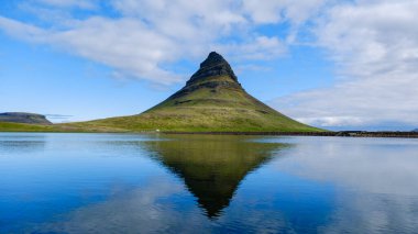 Kirkjufell Dağı sakin bir gölün yanında yükselir, İzlanda 'nın sakin sularında yansıyan ikonik şekli