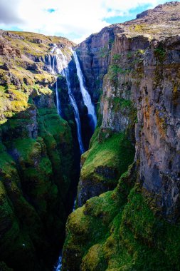 Glymur şelalesi, İzlanda 'daki yemyeşil bitki örtüsüyle çevrili engebeli uçurumlardan aşağı yuvarlanıyor. Bu doğa harikası açık bir günde İzlanda topraklarının saf güzelliğini gösteriyor..