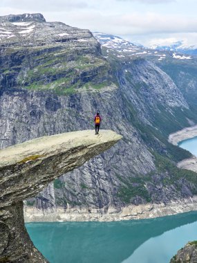 Yalnız bir maceraperest, sakin Lysefjord 'a tepeden bakan Norveç' in Trolltunga yürüyüşünün kenarında güvenle durur..