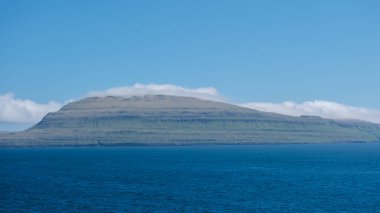 Slaettaratindur Dağı 'nın nefes kesici manzarası berrak bir gökyüzü altında sakin mavi suların üzerinde yükseliyor..