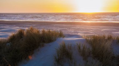 Nefes kesen bir günbatımı, Danimarka 'nın Vejers Strand kentindeki sakin plajın üzerinde canlı renklerle gökyüzünü boyuyor.