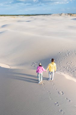Danimarka 'daki dalgalı Rabjerg Mil kum tepelerinde birlikte yürüyen iki kişinin ayak izleri arkalarında..