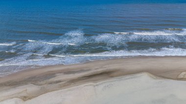 Danimarka kıyı şeridi, açık mavi bir gökyüzünün altında kumlu kıyılara vuran yumuşak dalgalarla sabah dinginliğini davet ediyor. Plaj aşıkları ve doğa meraklıları için mükemmel. Hvide Sande Kuzey Jutland Danimarka