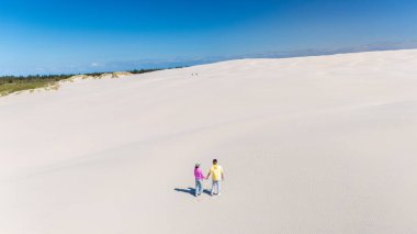 Bir çift, Danimarka 'nın Rabjerg Mile bölgesindeki kumullarda el ele yürür. Parlak mavi gökyüzü, doğanın ve aşkın güzelliğini gözler önüne seren bu huzurlu ana çarpıcı bir zemin hazırlar..