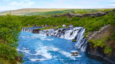 Barnafoss ve Hraunfossar 'ın büyüleyici şelalelerine şahit olun. Turkuaz nehrine dökülüyorlar, İzlanda' nın yemyeşil ve kayalık arazisi büyüleyici manzaralarla çevrili..
