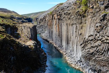 Studlagil Kanyonu 'nun çarpıcı özelliklerini keşfedin, kristal berrak suyun bazalt sütunlar arasında aktığı. Doğa meraklıları İzlanda 'nın engebeli arazisi boyunca yürüyüş yaparlar.