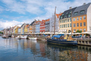 Nyhavn, Copenhagen, Denmark, 12 July 20204: harming, colorful buildings lining the harbor. Boats gently sway in the water, inviting visitors to enjoy this serene atmosphere.