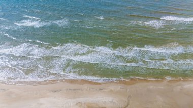 Yumuşak dalgalar, Danimarka kıyıları boyunca kumlu plajlarda yuvarlanarak doğanın güzelliğini yakalıyor. Canlı turkuaz su, berrak gökyüzünün altındaki altın kıyılarla kusursuz bir şekilde harmanlanır..