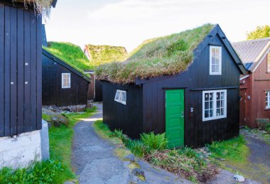 Faroe Adaları 'ndaki geleneksel çim çatılı evlerin cazibesini keşfedin. Yeşillik bu eşsiz yapıları çevreleyerek, yerel mimarinin ve mirasın güzelliğini gözler önüne seriyor..
