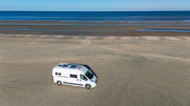 Romo Danimarka 'nın geniş kumlu sahillerinde arka planda parlak mavi okyanuslar olan yalnız bir karavan sürüyordu. Güneşli gökyüzü sakin atmosferi güçlendirir, açık hava maceralarına davetiye çıkarır..