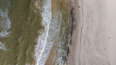 Titrek dalgalar Danimarka 'nın yumuşak kumlu sahillerine yavaşça akarak sakin bir atmosfer yaratıyor. Yalnız bir figür su kenarında yürüyor, doğaya dalmış güzelliğe..