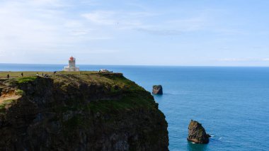 Ziyaretçiler, İzlanda 'nın önde gelen isimlerinden Dyrholaey' in nefes kesici manzarasına hayran kaldılar. Simgesel deniz feneri sonsuz okyanusun ve engebeli uçurumların arka planında gururla durur..