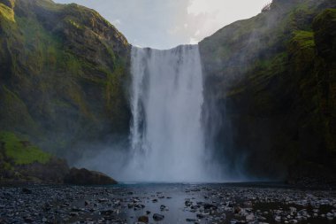 Skogafoss şelalesi büyüleyici güzelliğini gözler önüne seriyor. Su kayalık uçurumlarda zarifçe yuvarlanıyor ve İzlanda 'da sisli bir atmosfer yaratıyor.